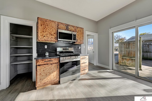 kitchen with tasteful backsplash, wood-type flooring, and appliances with stainless steel finishes