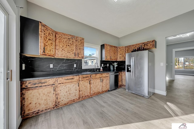 kitchen with plenty of natural light, backsplash, appliances with stainless steel finishes, and light hardwood / wood-style flooring