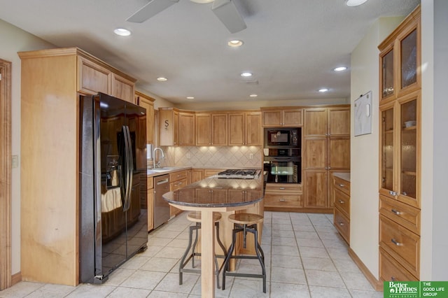 kitchen featuring a center island, a kitchen bar, decorative backsplash, light tile patterned floors, and black appliances