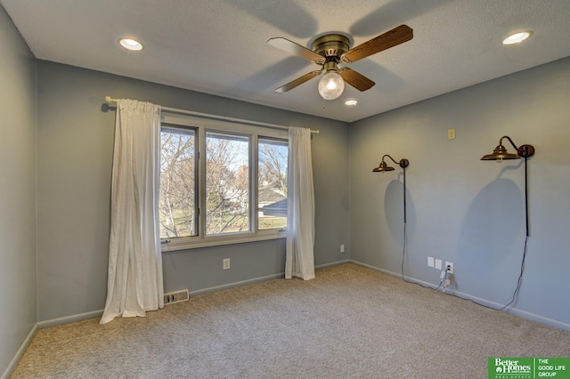 carpeted spare room featuring a textured ceiling and ceiling fan