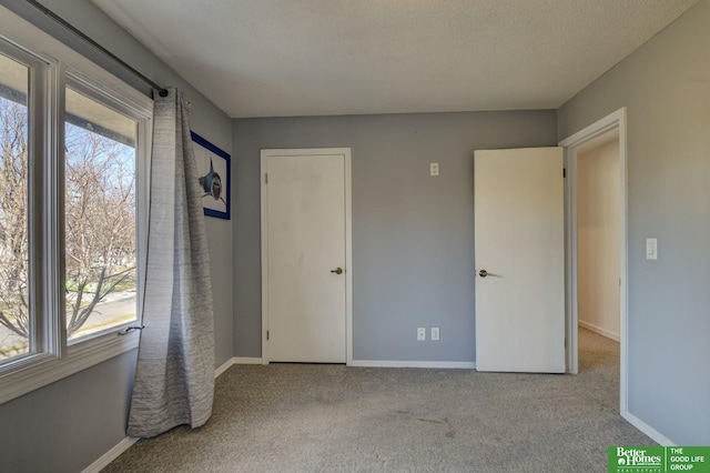 unfurnished bedroom with a textured ceiling and light colored carpet