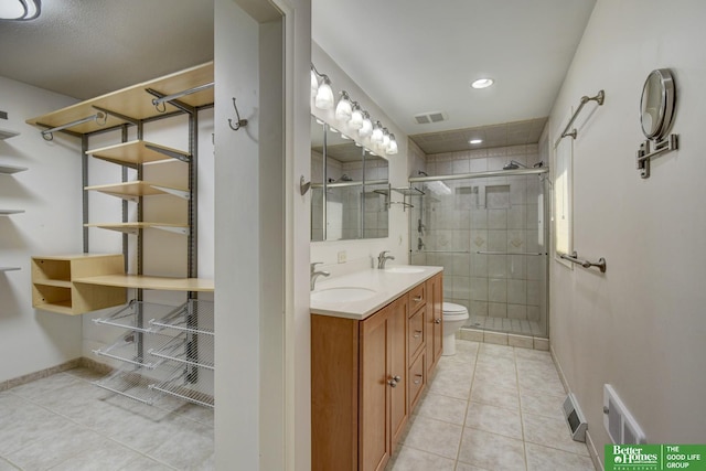 bathroom with tile patterned flooring, vanity, a shower with door, and toilet