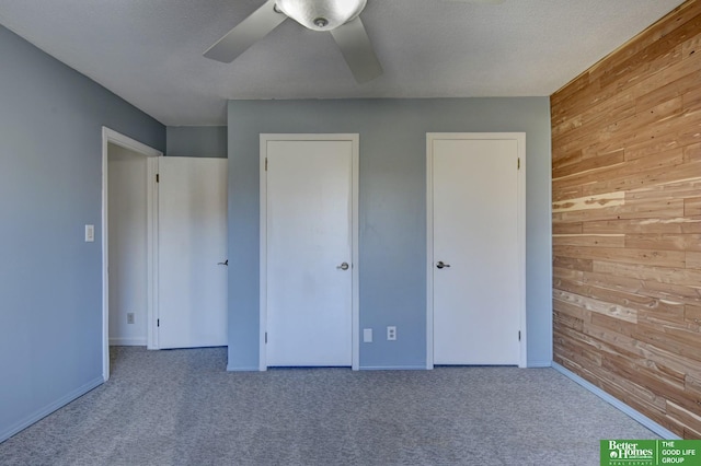 unfurnished bedroom with wooden walls, ceiling fan, and a textured ceiling