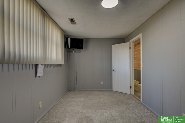 interior space featuring light colored carpet and a textured ceiling