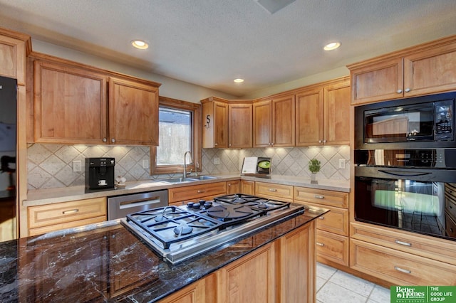 kitchen featuring backsplash, dark stone counters, sink, black appliances, and light tile patterned floors