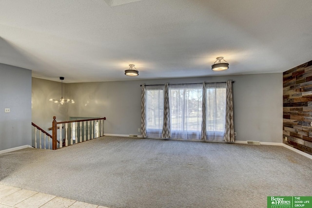 unfurnished room featuring carpet flooring, a notable chandelier, and a textured ceiling