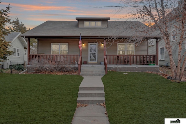 bungalow with covered porch and a yard