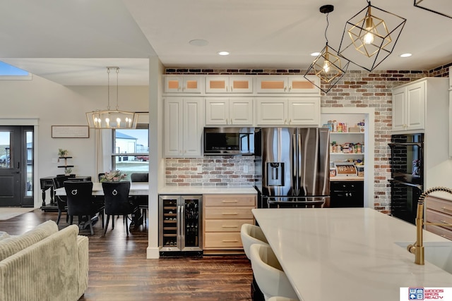 kitchen featuring white cabinetry, beverage cooler, brick wall, decorative light fixtures, and appliances with stainless steel finishes