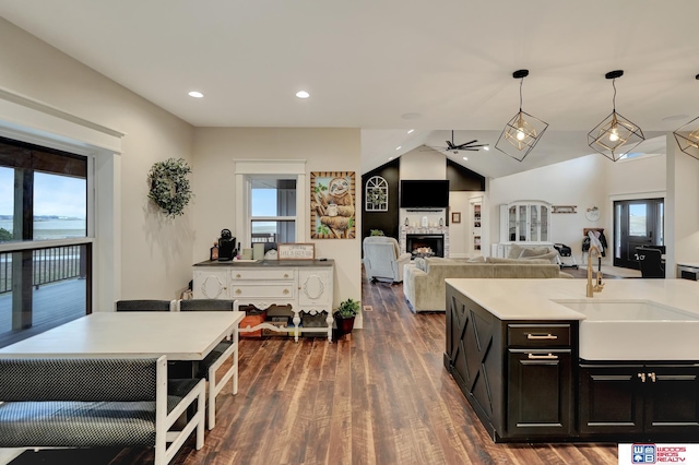 kitchen featuring a center island with sink, sink, ceiling fan, dark hardwood / wood-style floors, and decorative light fixtures