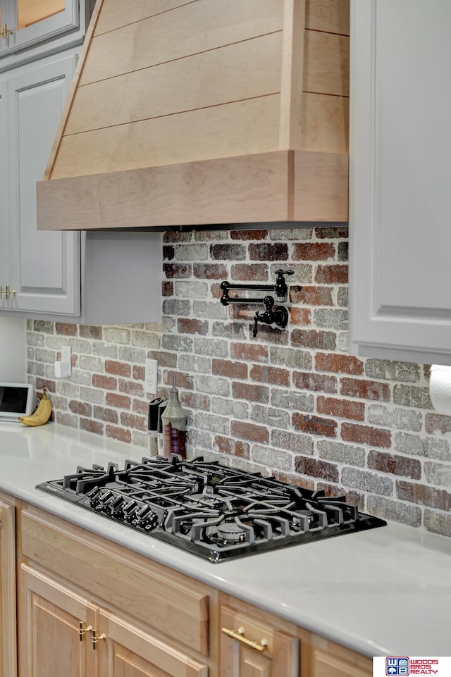 kitchen with decorative backsplash, light brown cabinetry, gas stovetop, and custom range hood