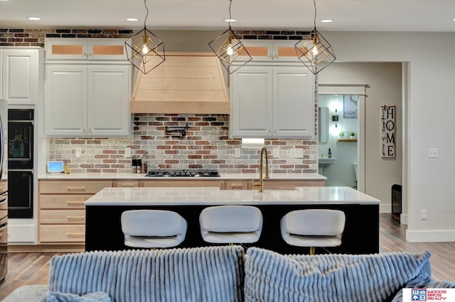 kitchen with black appliances, an island with sink, and hanging light fixtures