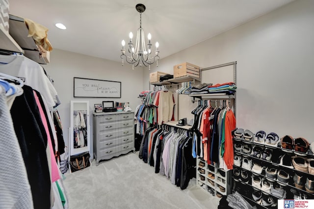 walk in closet with light carpet and a chandelier