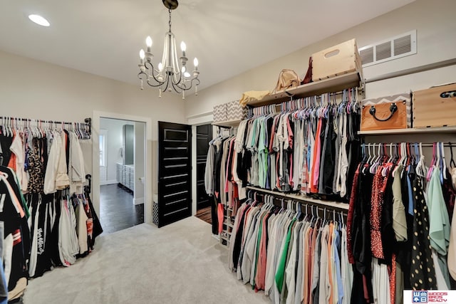 walk in closet featuring carpet and a chandelier