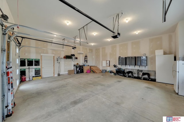 garage featuring white refrigerator and a garage door opener