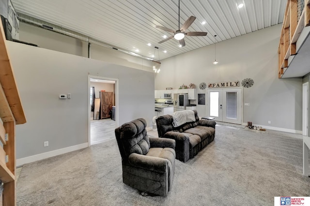 carpeted living room featuring french doors, ceiling fan, wooden ceiling, and a high ceiling