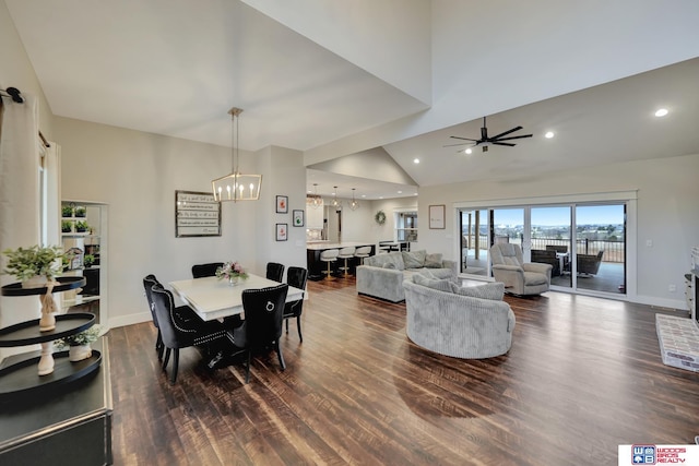 dining area with dark hardwood / wood-style flooring, ceiling fan with notable chandelier, and high vaulted ceiling