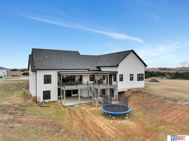 rear view of house with a trampoline, a patio, and a wooden deck