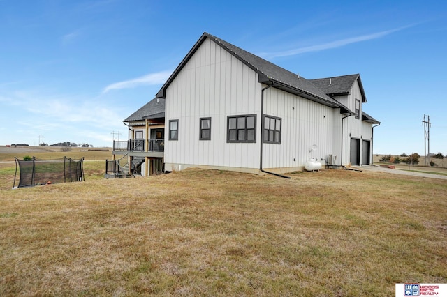 view of side of home featuring a trampoline, a yard, a wooden deck, and a garage