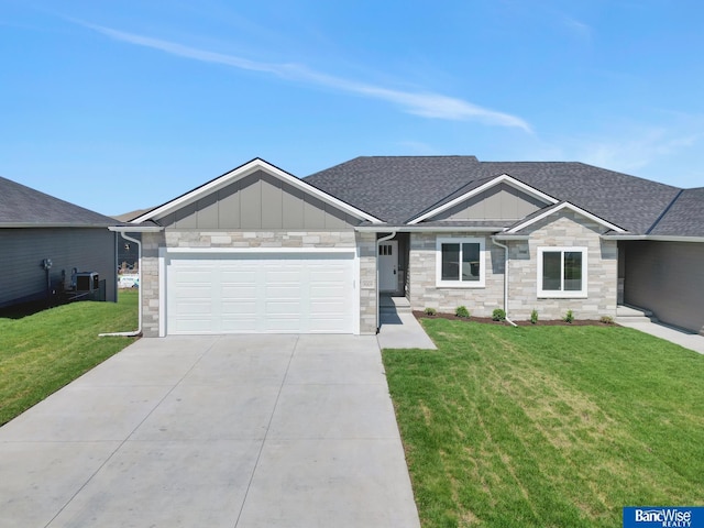 view of front of home with a front yard, central AC, and a garage