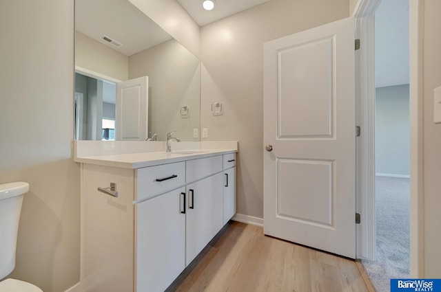 bathroom with hardwood / wood-style flooring, vanity, and toilet