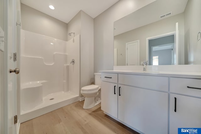 bathroom featuring vanity, toilet, wood-type flooring, and walk in shower