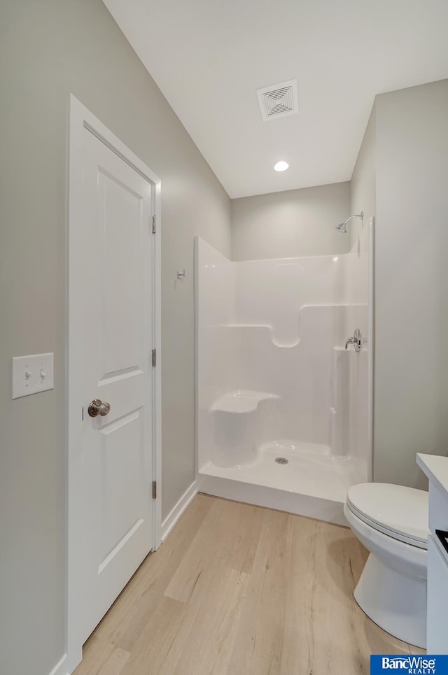 bathroom with a shower, toilet, vanity, and hardwood / wood-style flooring