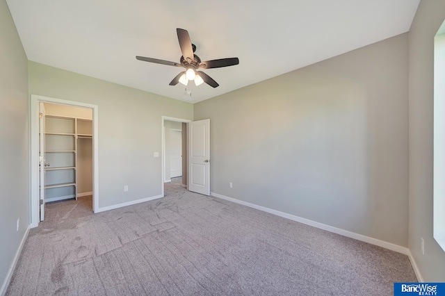 unfurnished bedroom with a closet, light colored carpet, a spacious closet, and ceiling fan