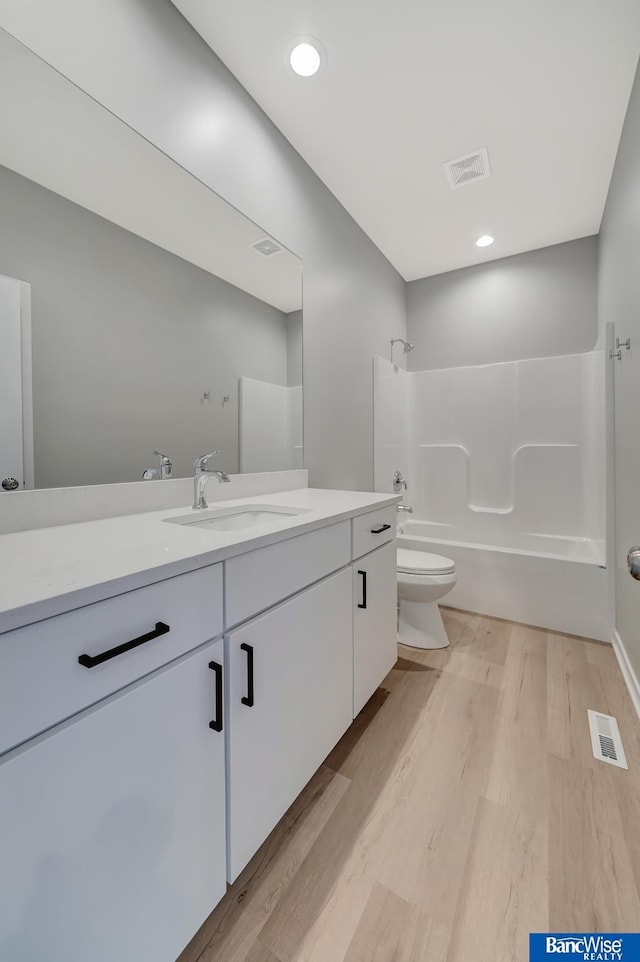 full bathroom with vanity, wood-type flooring, shower / bathtub combination, and toilet