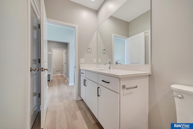 bathroom featuring toilet, vanity, and hardwood / wood-style flooring