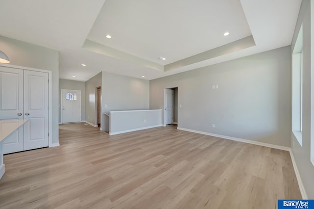 unfurnished living room with light hardwood / wood-style floors and a raised ceiling