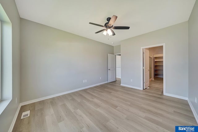 unfurnished bedroom featuring ceiling fan, a closet, a spacious closet, and light hardwood / wood-style flooring