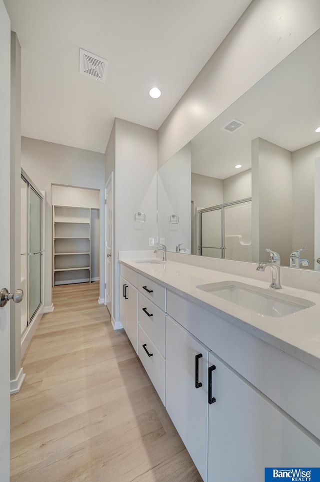 bathroom with hardwood / wood-style floors, vanity, and walk in shower