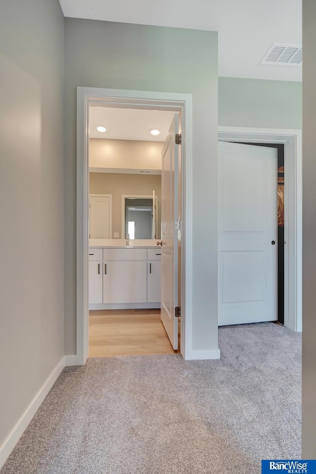 hallway featuring light carpet and sink