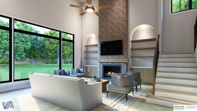 living room with plenty of natural light, a high ceiling, a fireplace, light hardwood / wood-style floors, and built in shelves