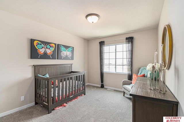 bedroom with carpet flooring, a crib, and a textured ceiling