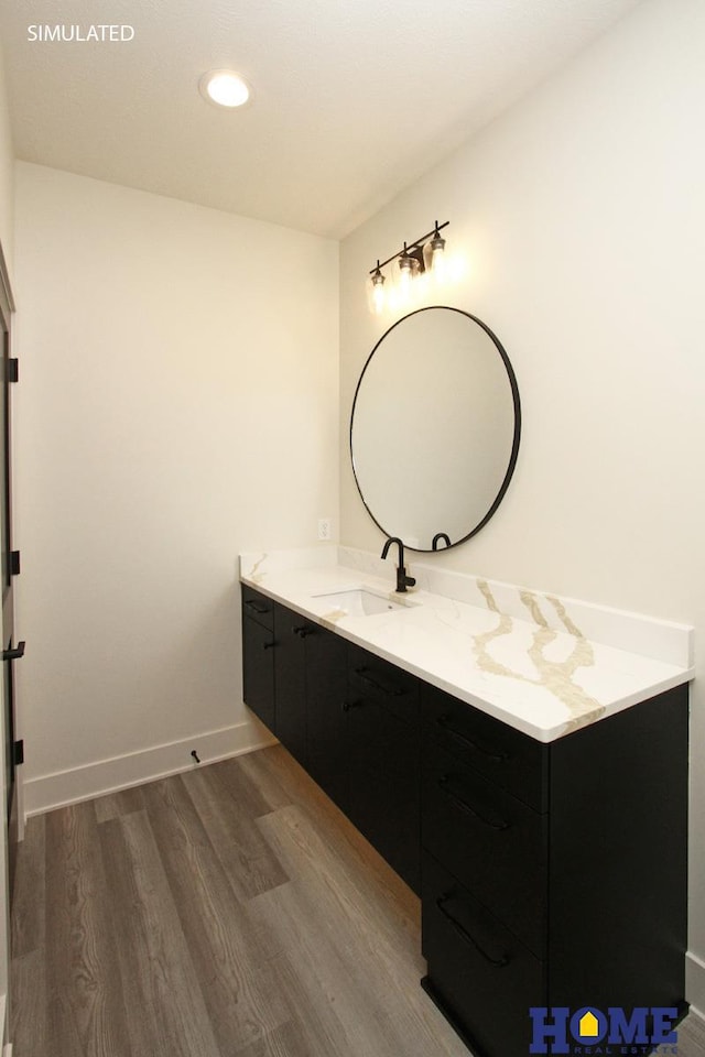 bathroom with recessed lighting, wood finished floors, vanity, and baseboards