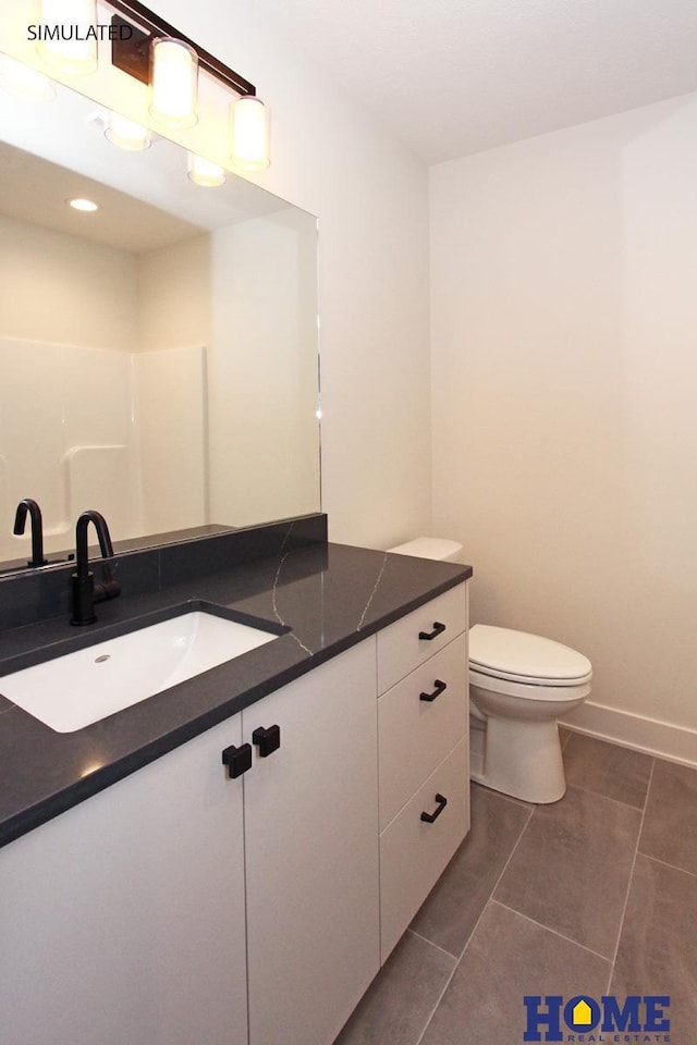 bathroom with toilet, baseboards, and vanity