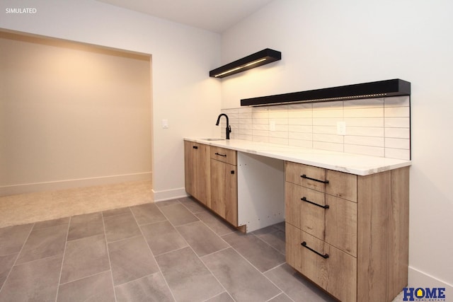 kitchen featuring baseboards, decorative backsplash, light countertops, dark tile patterned floors, and a sink