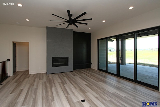 unfurnished living room with ceiling fan, a fireplace, and light hardwood / wood-style flooring