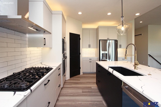 kitchen featuring a sink, white cabinets, range hood, black appliances, and decorative light fixtures