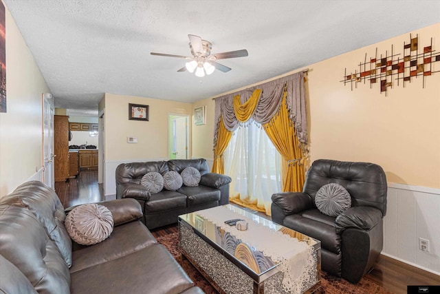 living room with ceiling fan, dark hardwood / wood-style flooring, and a textured ceiling