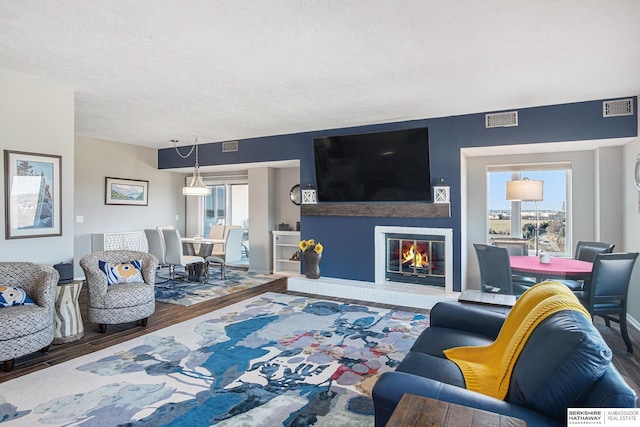 living room with hardwood / wood-style flooring, a fireplace, and a textured ceiling