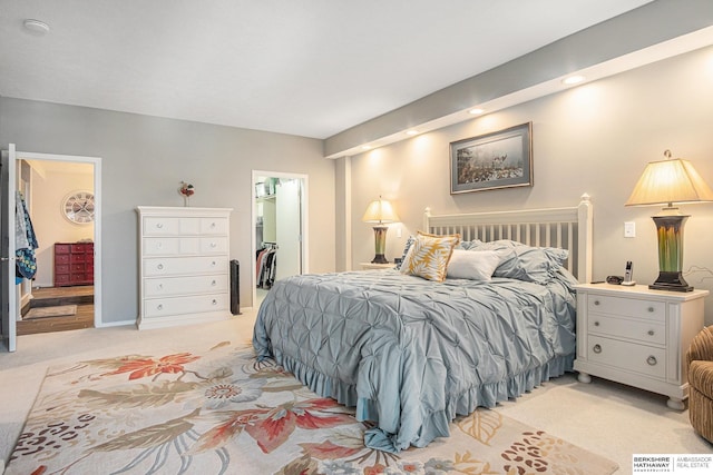 bedroom with a walk in closet, ensuite bathroom, a closet, and light colored carpet