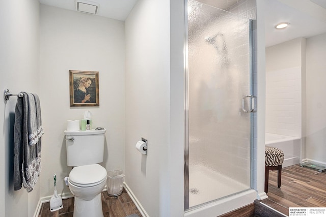 bathroom featuring hardwood / wood-style floors, toilet, and a shower with door