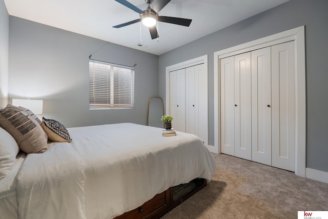 bedroom featuring light colored carpet, ceiling fan, and multiple closets