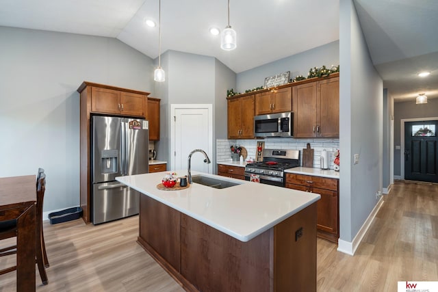 kitchen with pendant lighting, backsplash, a center island with sink, sink, and stainless steel appliances