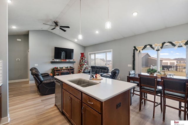 kitchen featuring pendant lighting, dishwasher, sink, light hardwood / wood-style flooring, and an island with sink