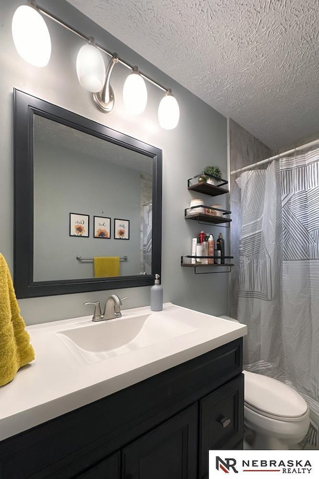 bathroom with a shower with curtain, vanity, toilet, and a textured ceiling