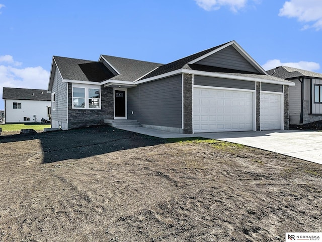 single story home featuring entry steps, stone siding, driveway, and an attached garage