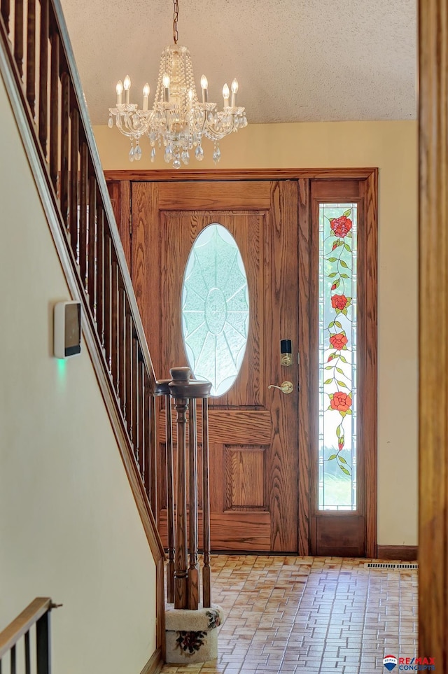 foyer entrance with a textured ceiling and an inviting chandelier